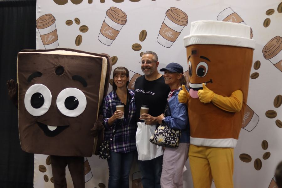 Festival mascots Chunk and Bean posing with guests at the photo wall.