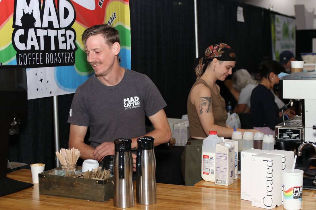 Two vendors standing behind their coffee roasting booth, ready to serve customers.